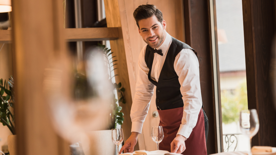 Illustrasjonsbilde fra en restaurant: Bilde av en servitør som dekker et bord.