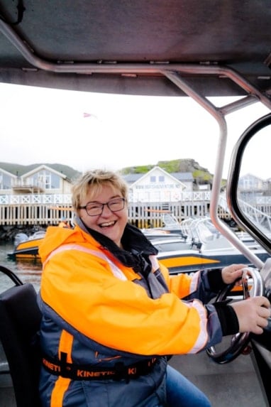 Smilende kvinne som styrer en båt. Foto.