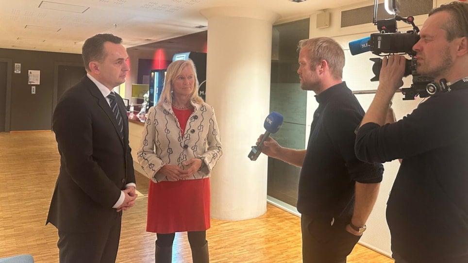 En mann og en kvinne som blir intervjuet av en journalist med NRK-mikrofon, mens en mann med kamera står bak dem. Foto