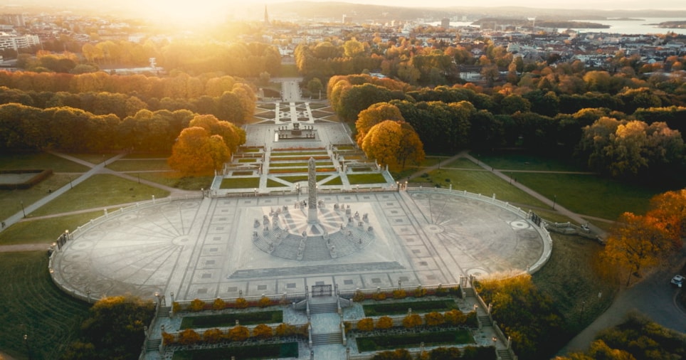 Overblikk over Vigelandsparken i Oslo en høstdag med fargerike trær som omkranser monolitten.