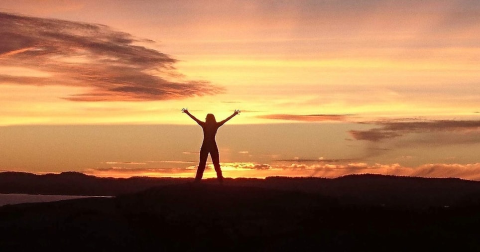 Dameskikkelse med opp i været i solnedgang.