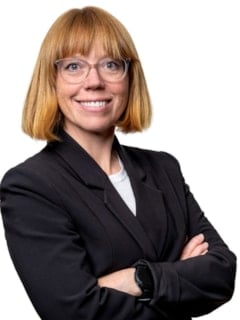 En kvinne med briller og mørk dressjakke. Foto